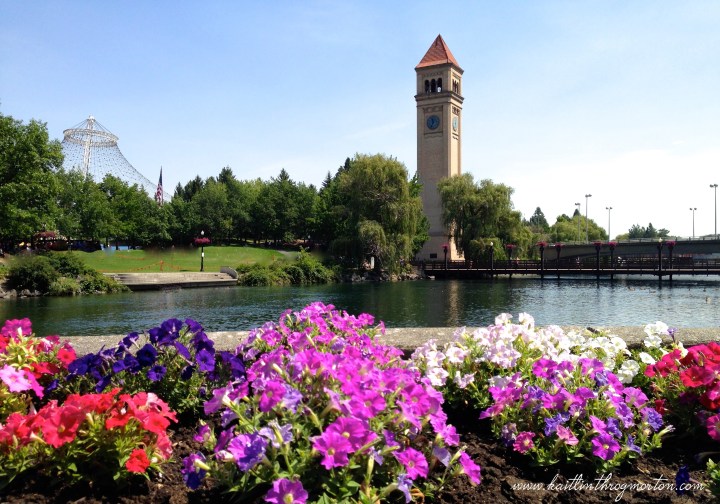 As seen from the main downtown entrance to Riverfront Park, the Clock Tower rises above patches of flowers.